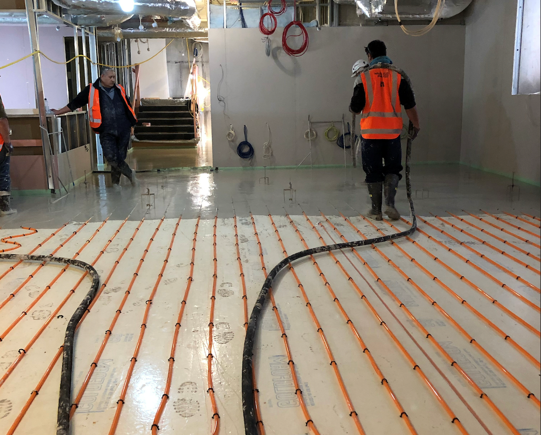 Concrete workers pours floor levelling compound